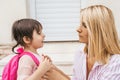 Side view of mother preparing her kid daughter to going to kindergarten sitting on stairs against home outdoor. Portrait of cute Royalty Free Stock Photo