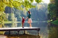 Side view of a mother and a young son standing together on a wooden bridge on a lake in the summer. Family, summer, vacation, love Royalty Free Stock Photo