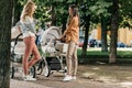 side view of mothers talking and standing with baby strollers