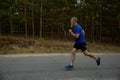 Side view motion shot of retired senior sportsman running among road