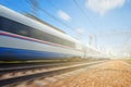 Side view of the moving ultra high speed train runs on rail way with railway infrastructure in the blurred background with flare e Royalty Free Stock Photo