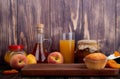 side view of a muffin on wooden board and fresh ripe peaches with a glass of peach juice and peach jam in a glass jar on rustic