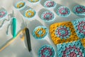 Side view of multicolored crochet patterns and two hooks with crochet chains started, on white surface with rough texture, bold Royalty Free Stock Photo