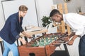 side view of multicultural businessmen playing table football together while resting