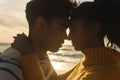 Side view of multiracial couple romancing while hugging each other at beach during sunset