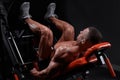 Side view of muscular ethnic male athlete lying on leg press machine and pumping muscles during workout in gym Royalty Free Stock Photo