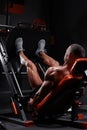 Side view of muscular ethnic male athlete lying on leg press machine and pumping muscles during workout in gym Royalty Free Stock Photo