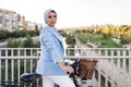 Side view of a muslim woman standing with her bike on a footbridge looking to a side Royalty Free Stock Photo