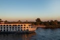 Side view of nile cruise ship sailing throught the river in golden hour at sunset with beautiful light and vegetation Royalty Free Stock Photo