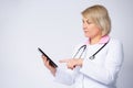 Side view of a nurse or doctor uses a digital tablet, forefinger to screen, isolated on a gray background. Physician