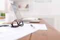 Side view of office desk with glasses, laptop and other items