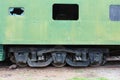 Side view of an old green train passenger car with a broken window, detailing the wheel and undercarriage configuration Royalty Free Stock Photo