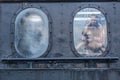 Side view of old train cabin window with reflection of two children