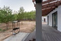 Side view of an open veranda in front of a modern forest cottage. Pine young forest under the sunset rays in the