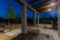 Side view of an open veranda in front of a modern forest cottage. Pine young forest under the sunset rays in the
