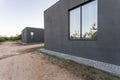 Side view of an open veranda in front of a modern forest cottage. Pine young forest under the sunset rays in the