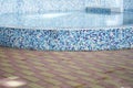 Side view of an outdoor swimming pool with blue and white mosaic ceramic tiles, with blue water. Background with copy Royalty Free Stock Photo