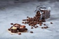 Side view of overturned glass jar with coffee beans and chocolate candies on white background, selective focus