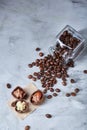 Side view of overturned glass jar with coffee beans and chocolate candies on white background, selective focus