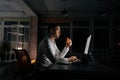 Side view of overworked businessman eating burger working on computer sitting on desk at office workplace late night in Royalty Free Stock Photo