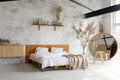 Side view of pacious airy white industrial loft bedroom with bed,  mirror and pampas grass decoration Royalty Free Stock Photo