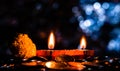 Side view of a pair of glowing Terracotta lamps with flower and coins, and blue colored bokeh in the background. Prosperity