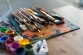 Side view of pallet with oil paint brushstrokes under paintbrush set in an art studio. Royalty Free Stock Photo