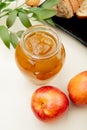 side view of peach jam in a glass jar and fresh ripe nectarines on white background Royalty Free Stock Photo