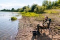 Side view of pensive bearded fisherman sitting on river bank on travel chair waiting for catch looking around. Royalty Free Stock Photo