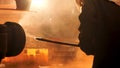 Side view of the perator remove waste from furnace pipe at the iron melting plant. Stock footage. Man worker in heat
