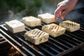 side view of person flipping tofu steaks on a grill