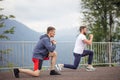 Side view of two caucasian sportsmen doing lungesin mountains. Royalty Free Stock Photo