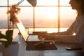 Side view photo of a female programmer using laptop, working, typing, surfing the internet at workplace.