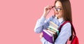 Side view photo of a school teenage girl in uniform with backpack and books giving a wink pushing back glasses, college