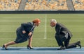 Side view photo of two business people kneeling opposite each other on race track