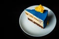 side view of piece of blue mousse cake on white plate