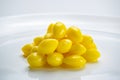 Side view pile of sweet yellow ginkgo seeds in white ceramic plate