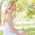 Side view of ponytailed calm woman meditating sitting in a park Royalty Free Stock Photo