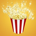 Side view popcorn in striped bucket explosionon yellow backgrou