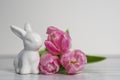 Porcelain Easter bunnies and same pastel colored pink white tulips. Royalty Free Stock Photo