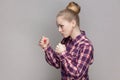 Angry woman with bun hairstyle standing with clenched fists, being ready to attack somebody. Royalty Free Stock Photo