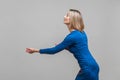 Side view portrait of assertive purposeful young businesswoman making effort to pull smth. indoor studio shot isolated on gray Royalty Free Stock Photo