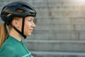 Side view portrait of attractive young woman, female cyclist wearing biking helmet smiling away while posing outdoors on