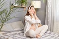 Side view portrait of beautiful relaxed pregnant brown haired caucasian woman sitting in bed listening to musing in headphones in