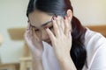 Side view portrait of beautiful young Asian girl sitting on floor and touching her temples feeling stress Royalty Free Stock Photo