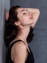 Side view portrait of beautiful young woman with brown hair standing against wall with her eyes closed pleasure Royalty Free Stock Photo