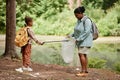 Black mother and daughter helping cleaning nature together and picking up trash Royalty Free Stock Photo