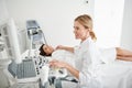 Young doctor using ultrasound scanner and examining thyroid of young lady