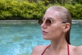 Side view portrait of confident sexy woman in pool looking away. Woman with wet hair wearing sunglasses and red swimsuit Royalty Free Stock Photo