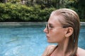 Side view portrait of confident sexy woman in pool looking away. Woman with wet hair wearing sunglasses and red swimsuit Royalty Free Stock Photo